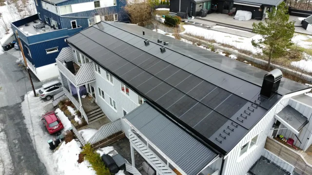 Aerial view of an apartment building with an integrated solar roof in winter.