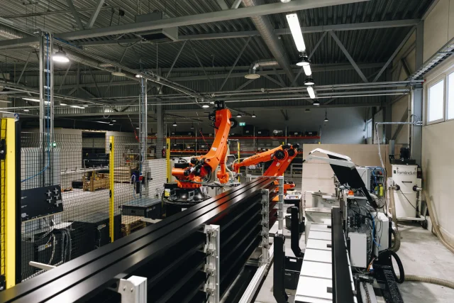 Wide view of industrial robots and metal profiles on the automated factory production line.