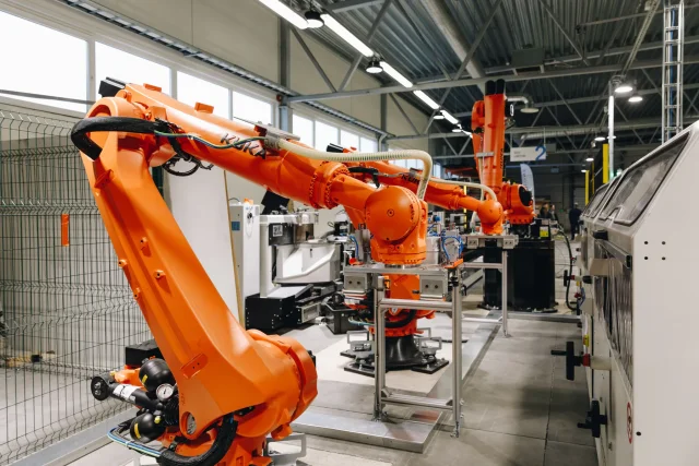 Multiple orange industrial robots on an automated solar roof production line.