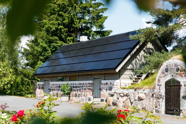 Granite stone building with an integrated solar roof surrounded by trees.