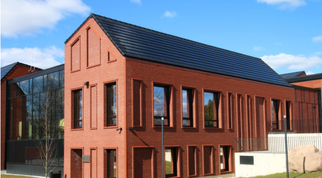 Brick building with an integrated solar tiled roof. Solarstone.