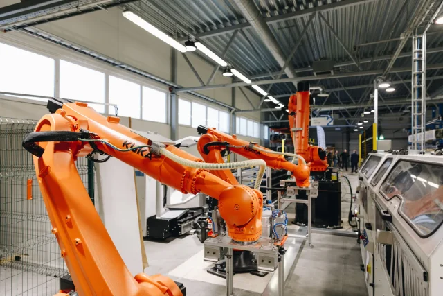 Orange industrial robot arms operating on the Solarstone factory production line.