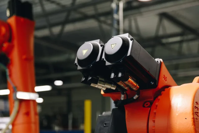 Close-up of drive components on an orange industrial robot in the Solarstone factory.