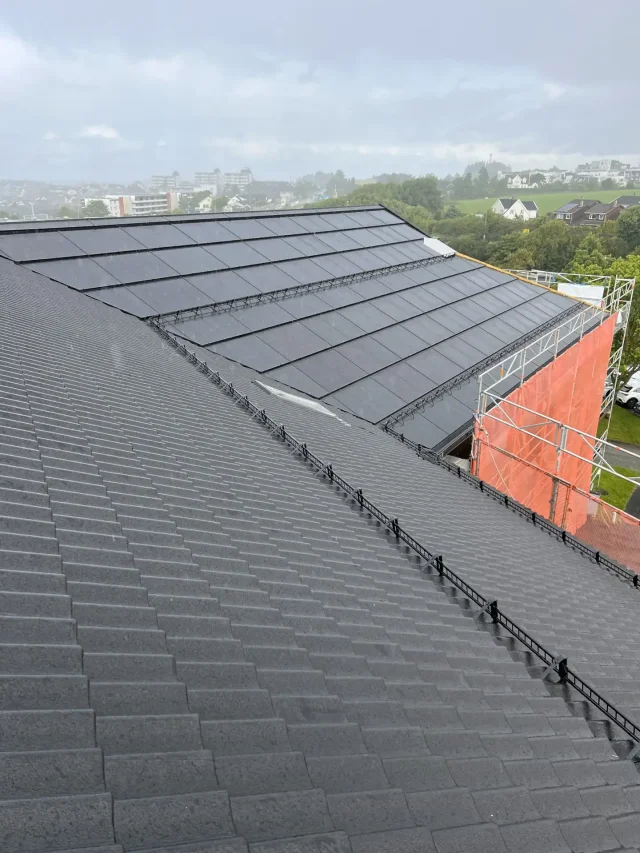 Integrated solar roof installation on a tiled building during rainy weather.