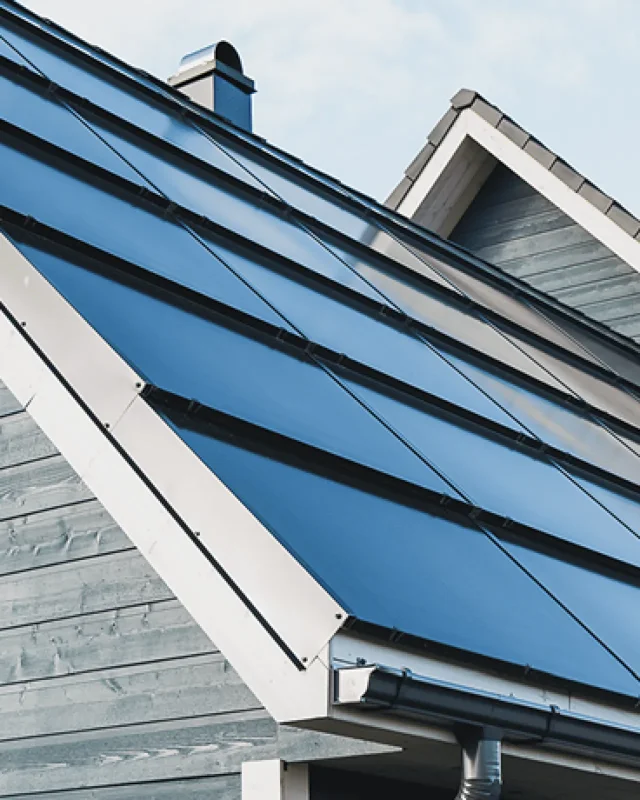 Nahaufnahme integrierter Solarmodule auf dem Dach eines Wohnhauses.