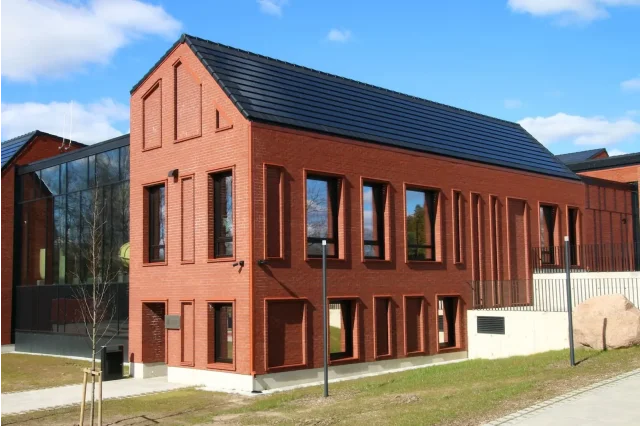 Red-brick building with an integrated solar tiled roof.