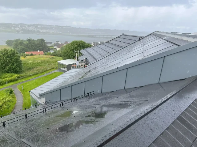 Rain-covered integrated solar roof overlooking a coastal landscape.