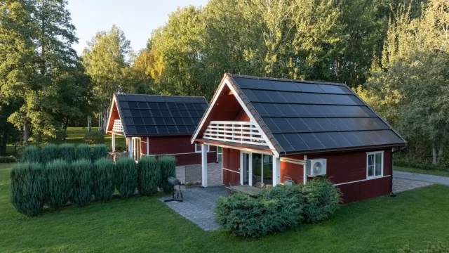 Close aerial view of two red cottages with integrated solar roofs.