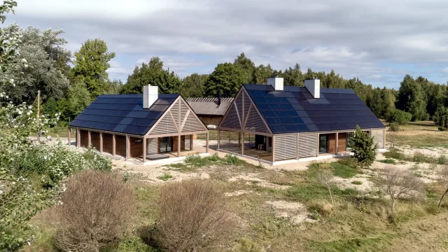 Aerial view of two timber seaside homes with full integrated solar roofs.