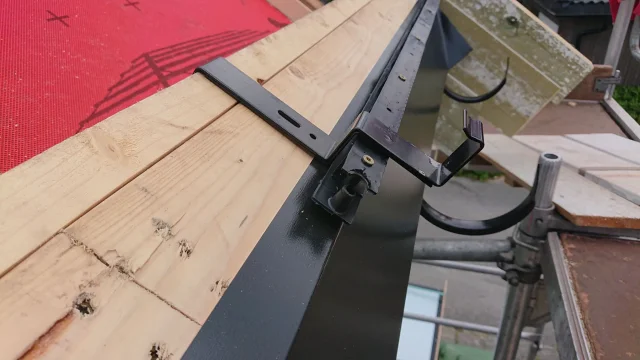 Close-up of corner flashing and electrical cabling on a timber roof deck.