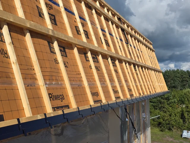 Black eave profile installed along exposed timber roof framing.