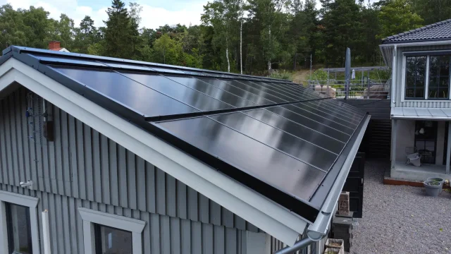 Side view of a grey wooden home with a completed Solar Full Roof™ installation.