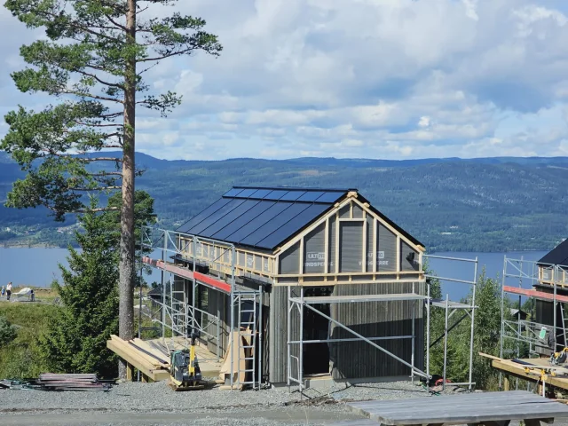 Small gabled home under construction with a Solar Full Roof™ installation overlooking a fjord.