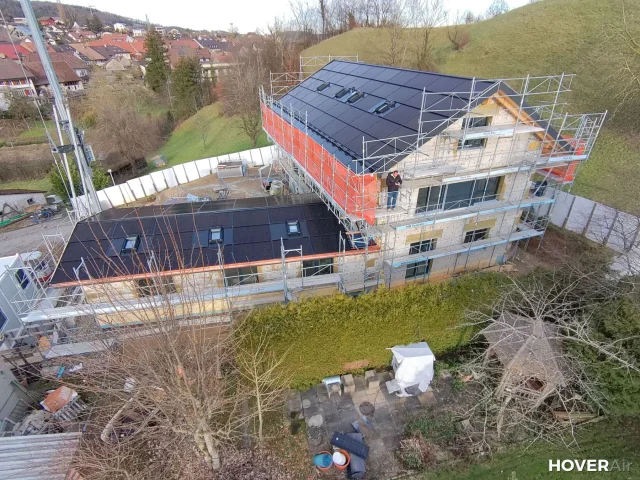 Aerial view of a Solar Full Roof™ installation on a scaffolded gabled home in Switzerland.