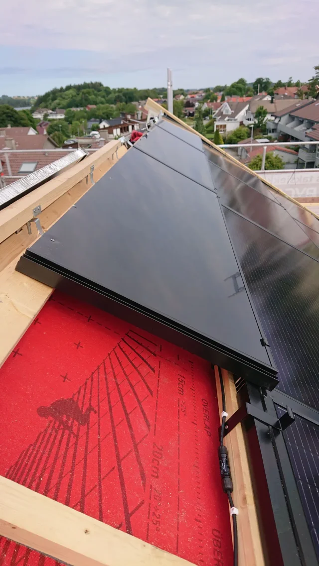 View along a long Solar Full Roof™ installation beside red roof underlay.