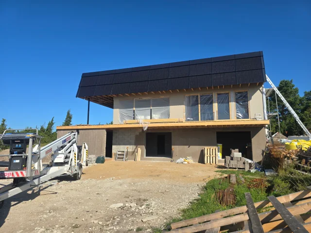 Front view of a modern building under construction with a Solar Full Roof™ installation.