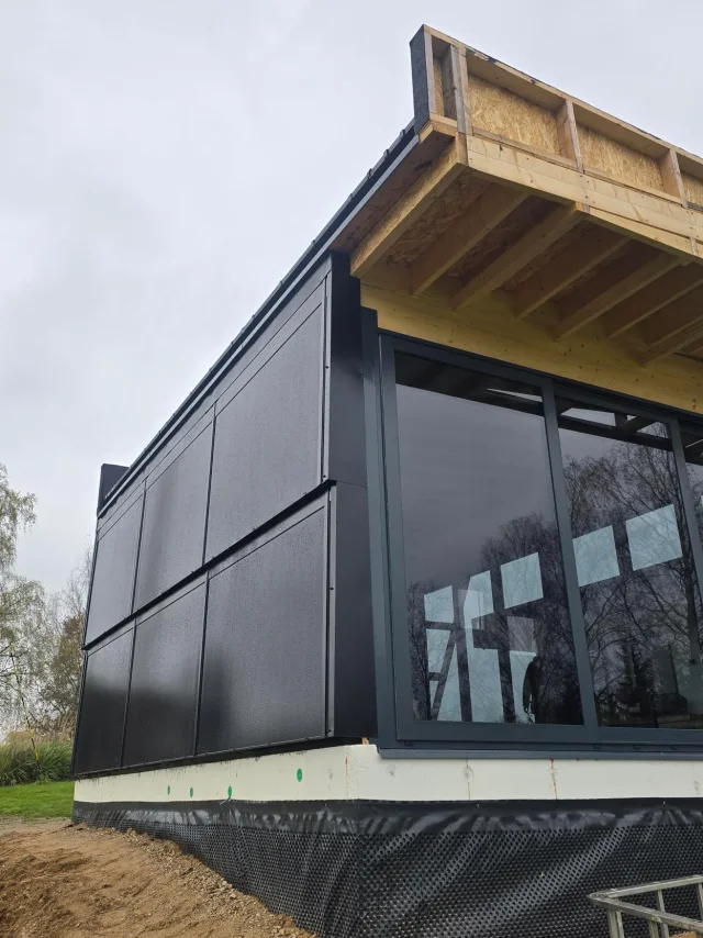 Modern building extension with black Solar Full Roof™ surfaces and floor-to-ceiling glazing.