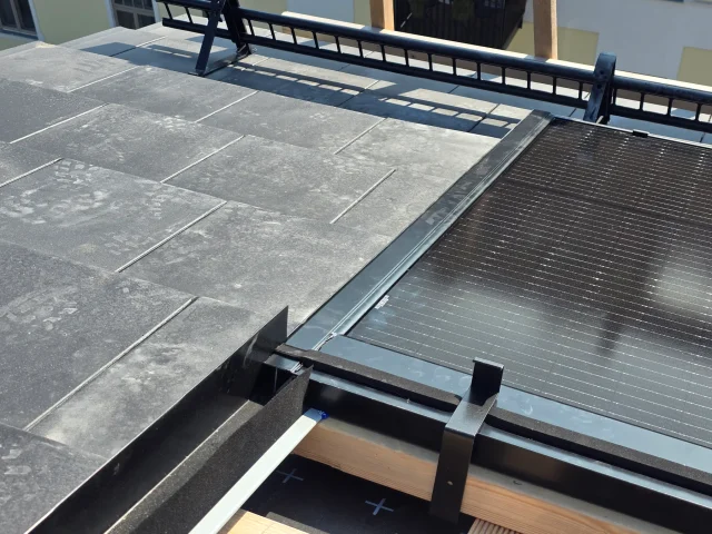 Metal edge rail joining a Solar Full Roof™ module to the adjacent tiled roof.