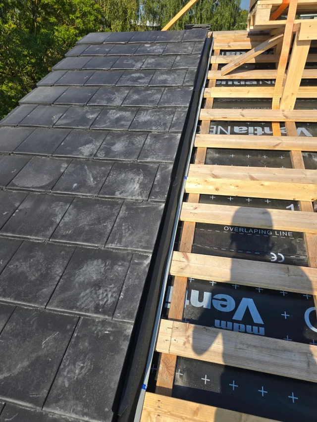 Partially installed Solar Full Roof™ modules beside exposed roof battens and tiles.