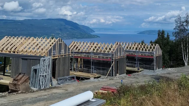 Timber roof framing for a Solar Full Roof™ project with mountains and water in the background.