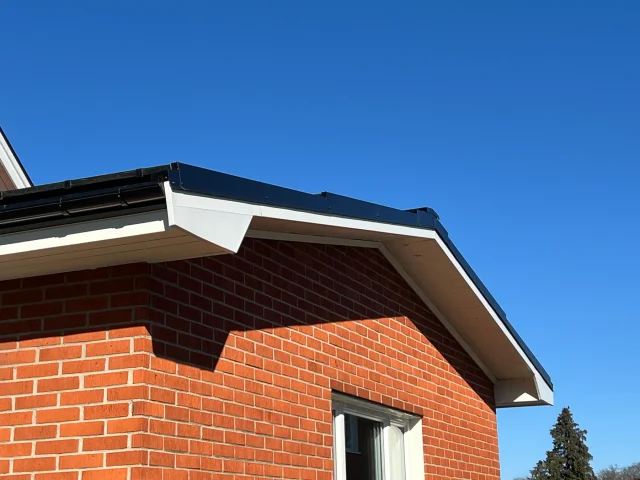 Red-brick home with a finished Solar Full Roof™ gable edge under a blue sky.