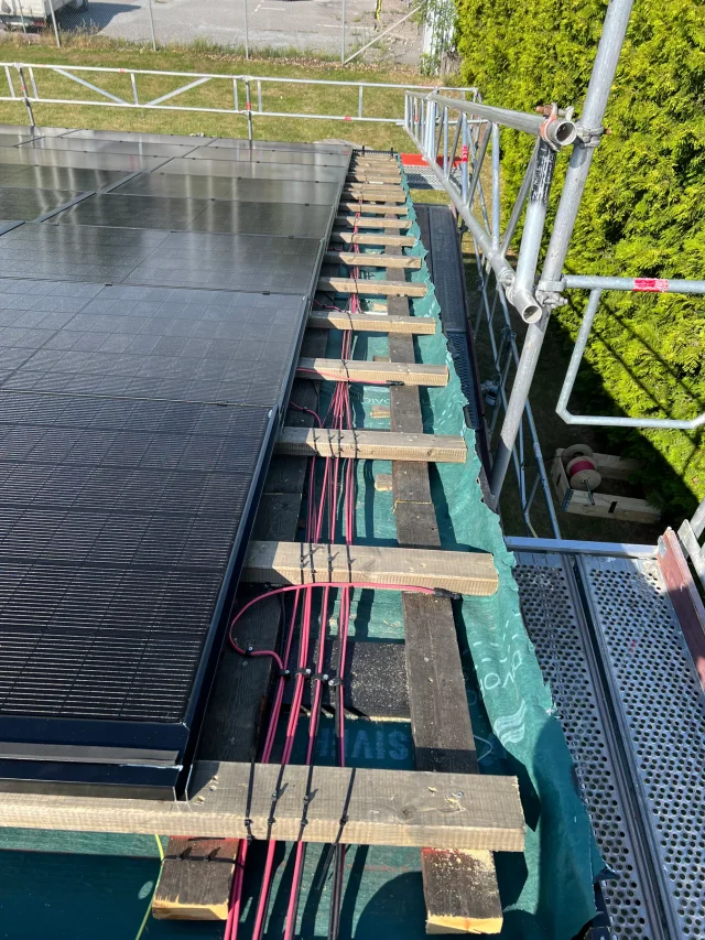 Solar Full Roof™ modules installed along the scaffolded edge of a partially battened roof.