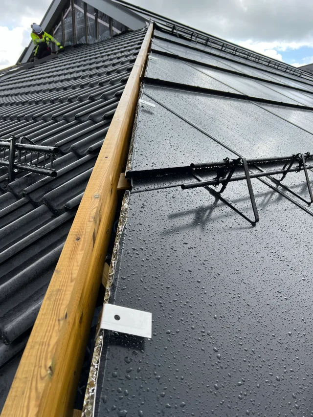 Close-up of side flashing being installed between Solar Full Roof™ modules and a tiled roof.