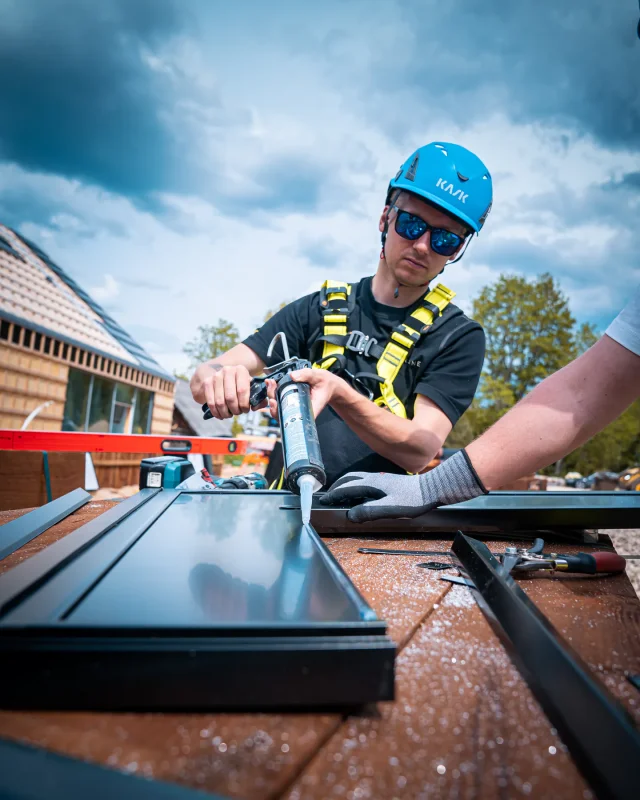 Installer applying silicone to a U-profile beside a Solar Full Roof™ module.