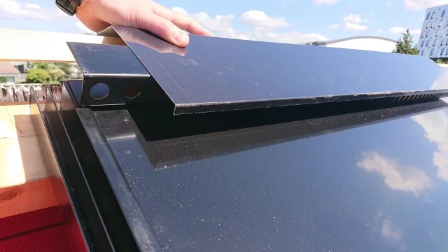 Hand positioning a black ventilation profile along a Solar Full Roof™ module edge.