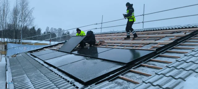 Installers securing Solar Full Roof™ modules on a snow-covered roof.