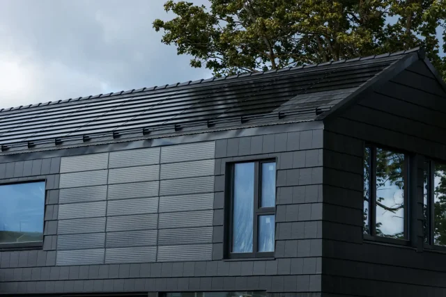 Solar panels integrated into the dark façade of a modern home with a Solar Tiled Roof™ installation.