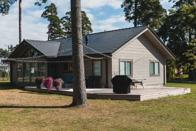 Grey home with a Solar Tiled Roof™ installation surrounded by pine trees.