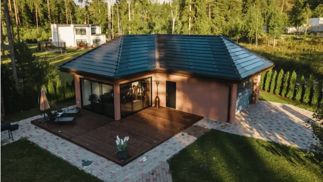 Aerial view of a single-story home with a Solar Tiled Roof™ installation on its hipped roof and a wooden terrace.