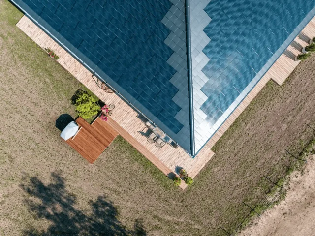 Overhead aerial view of a Solar Tiled Roof™ installation on a home with a wraparound wooden terrace.