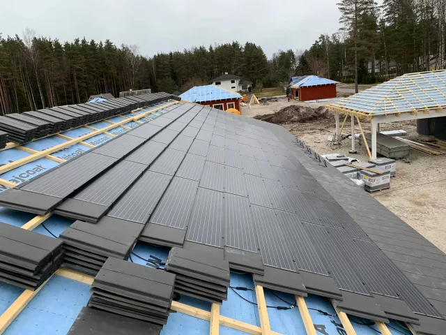 Partially completed Solar Tiled Roof™ installation with modules and roof tiles stacked on exposed battens.