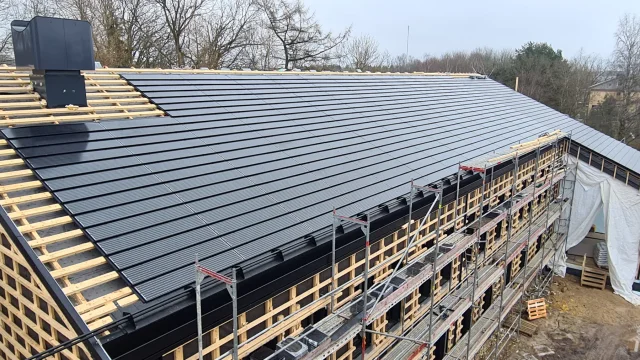 Solar Tiled Roof™ modules covering a large scaffolded building during installation.