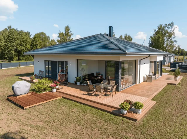 Aerial view of a modern bungalow with a Solar Tiled Roof™ installation and wraparound wooden terrace.