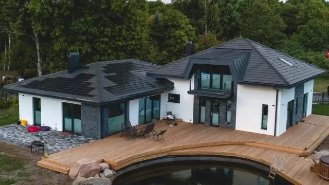 Aerial view of a modern multi-wing home with Solar Tiled Roof™ installations, a large wooden deck and a swimming pool.