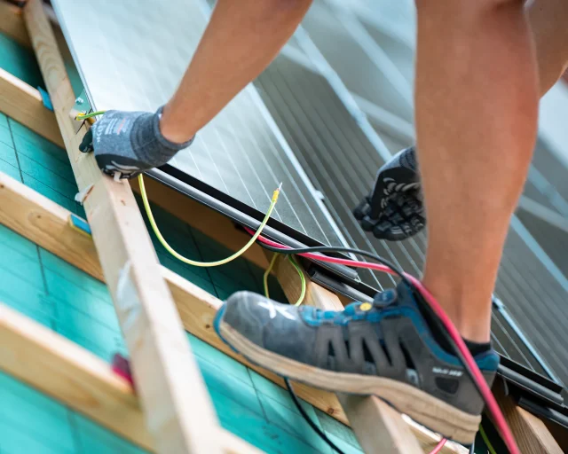 Installer routing electrical cables beneath a Solar Tiled Roof™ module on timber battens.