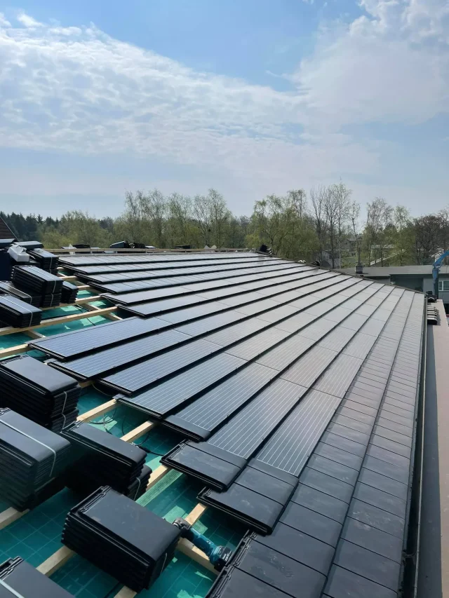 Rows of Solar Tiled Roof™ modules being integrated with dark roof tiles.