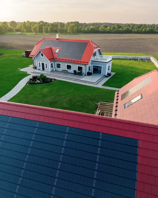 Aerial view of Solar Tiled Roof™ installations integrated into red roofs on a rural residential property.