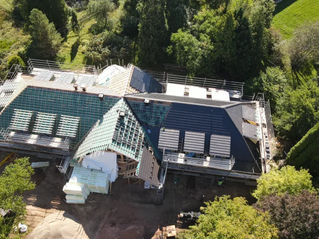 Aerial view of a large renovation project with a partial Solar Tiled Roof™ installation and scaffolding.