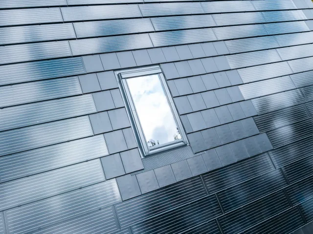 Close-up of a skylight surrounded by Solar Tiled Roof™ photovoltaic panels and matching dark roof tiles.