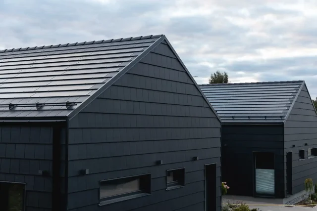 Solar Tiled Roof™ installations on two modern dark-clad homes.