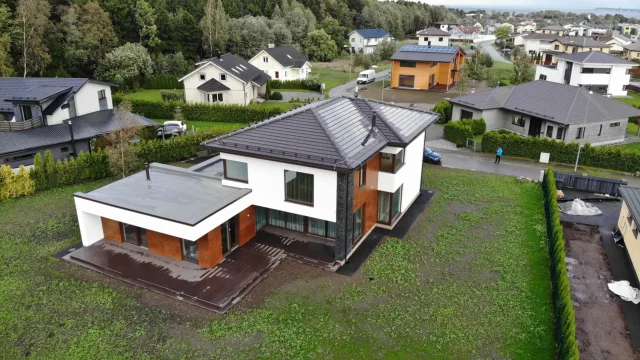 Aerial view comparing a Solar Tiled Roof™ on a modern home with conventional rooftop solar panels on a neighbouring house.