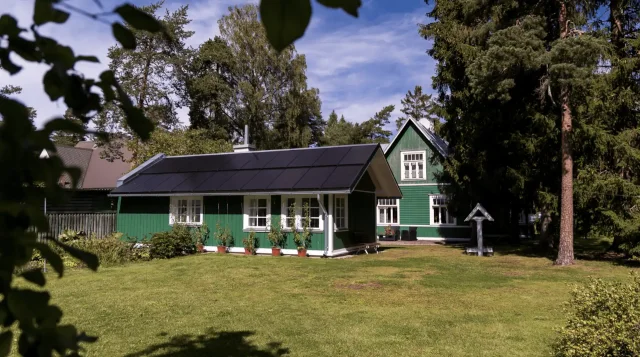 Traditional green wooden house with an integrated solar roof.