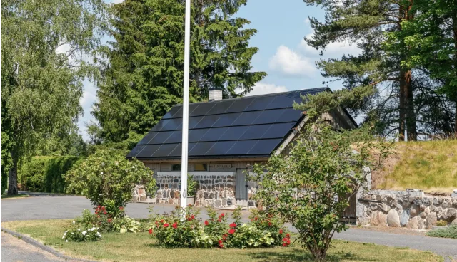 Traditional stone building with an integrated solar roof in a landscaped garden.