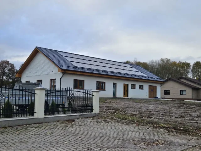 White house with solar panels integrated into a dark tiled roof.